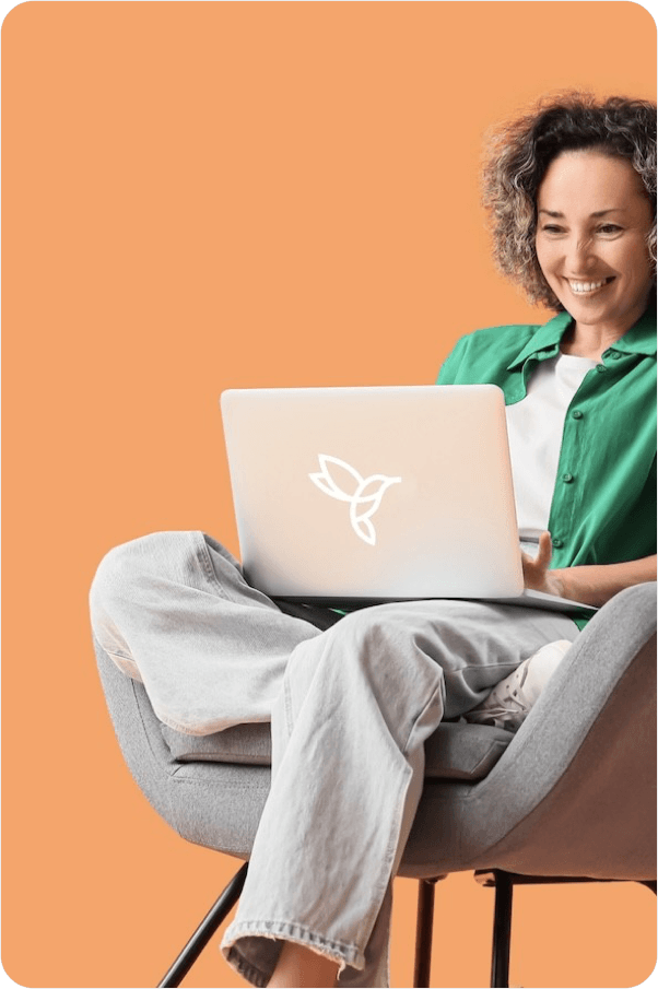 A woman working on a laptop while sitting comfortably in a chair.